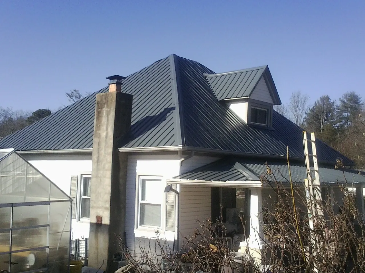 Dark blue standing seam metal roof on a white farmhouse with dormer — Slate & Tile Roof Repair by Roofing Brothers in Audubon